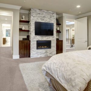 Bedroom with fireplace and television wall setup.